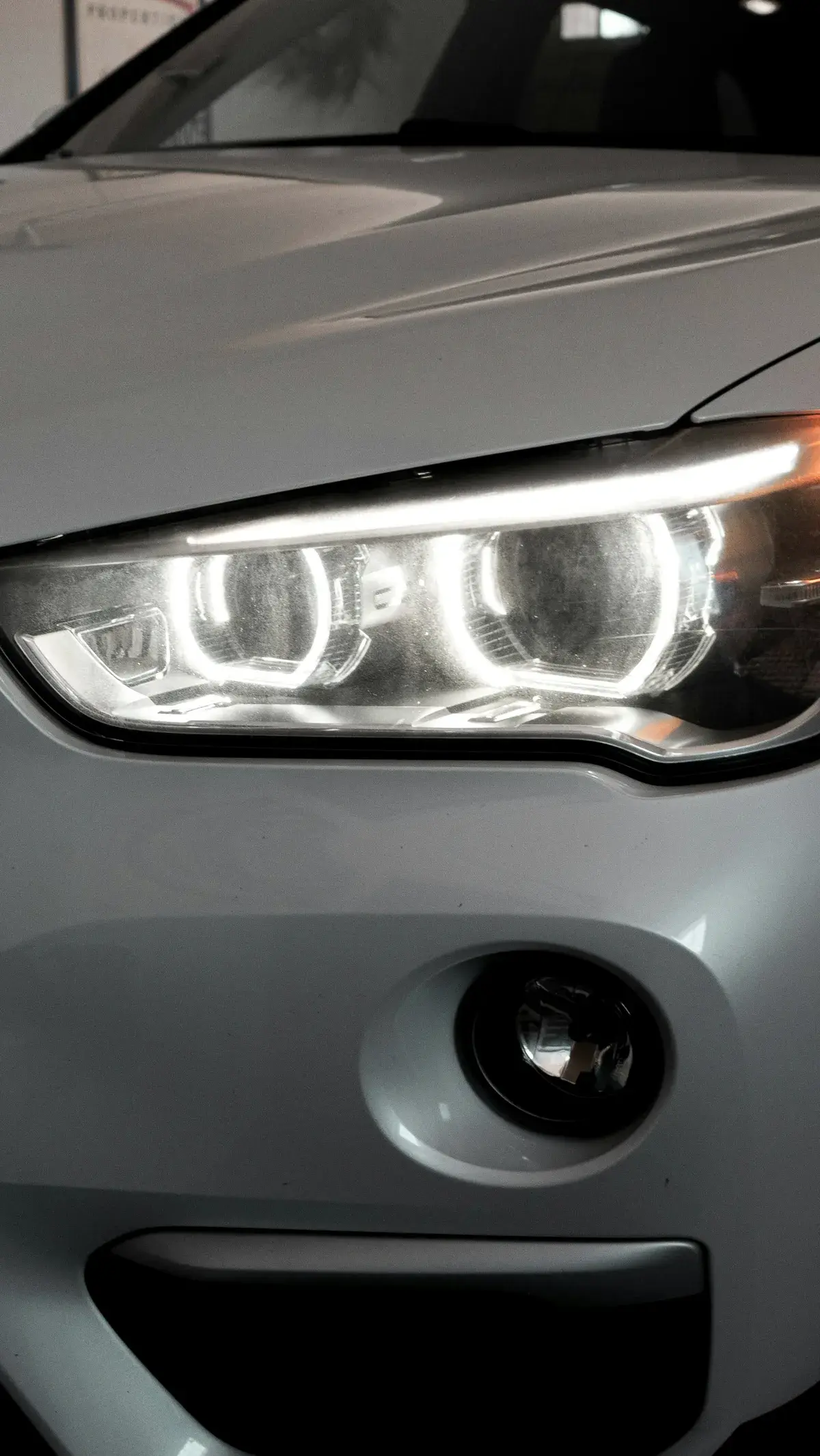 Farol de carro branco com anéis de luz de LED acesos. Imagem ilustrativa.