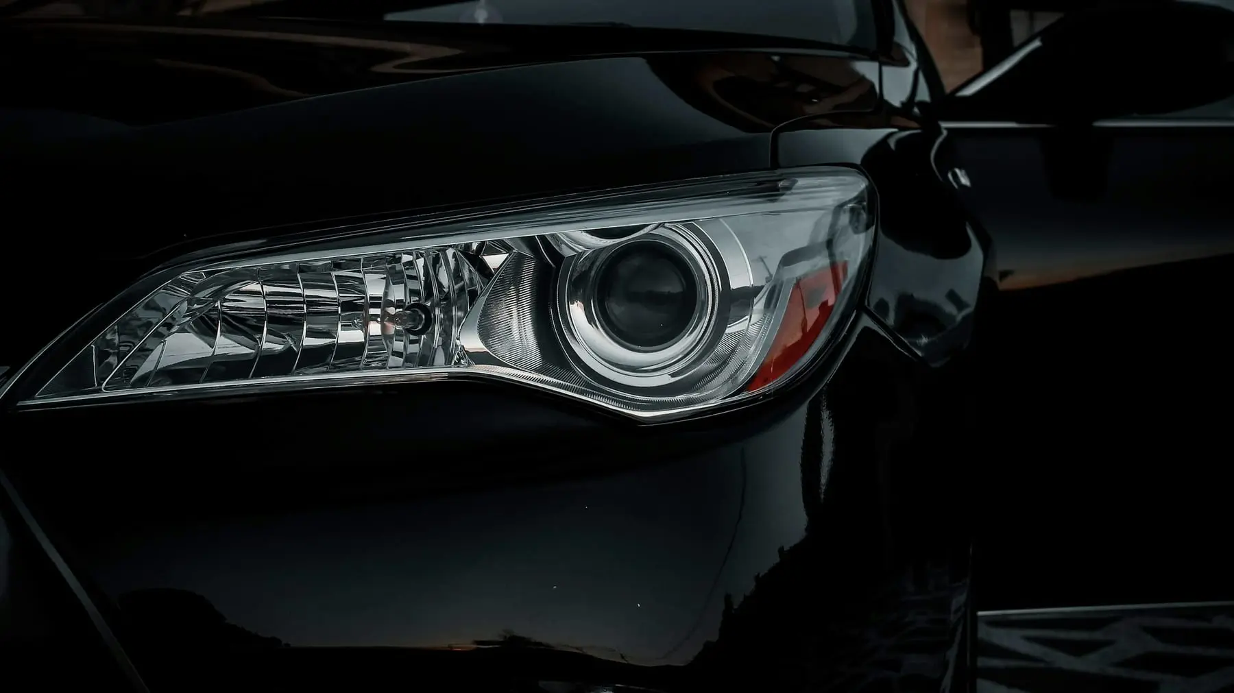 Farol dianteiro de um carro preto em close. Imagem ilustrativa.