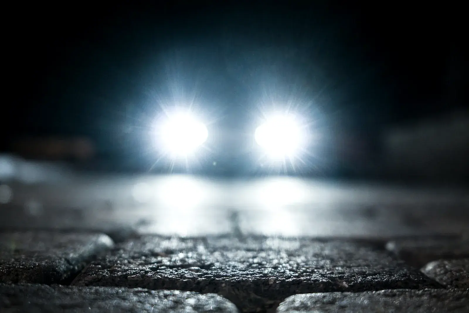 Par de faróis acesos com luz branca à noite. Imagem ilustrativa.