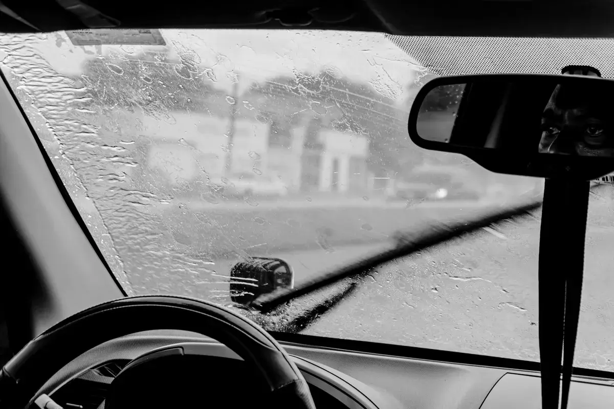 Limpadores tirando a chuva do para-brisa, em preto e branco. Imagem ilustrativa.