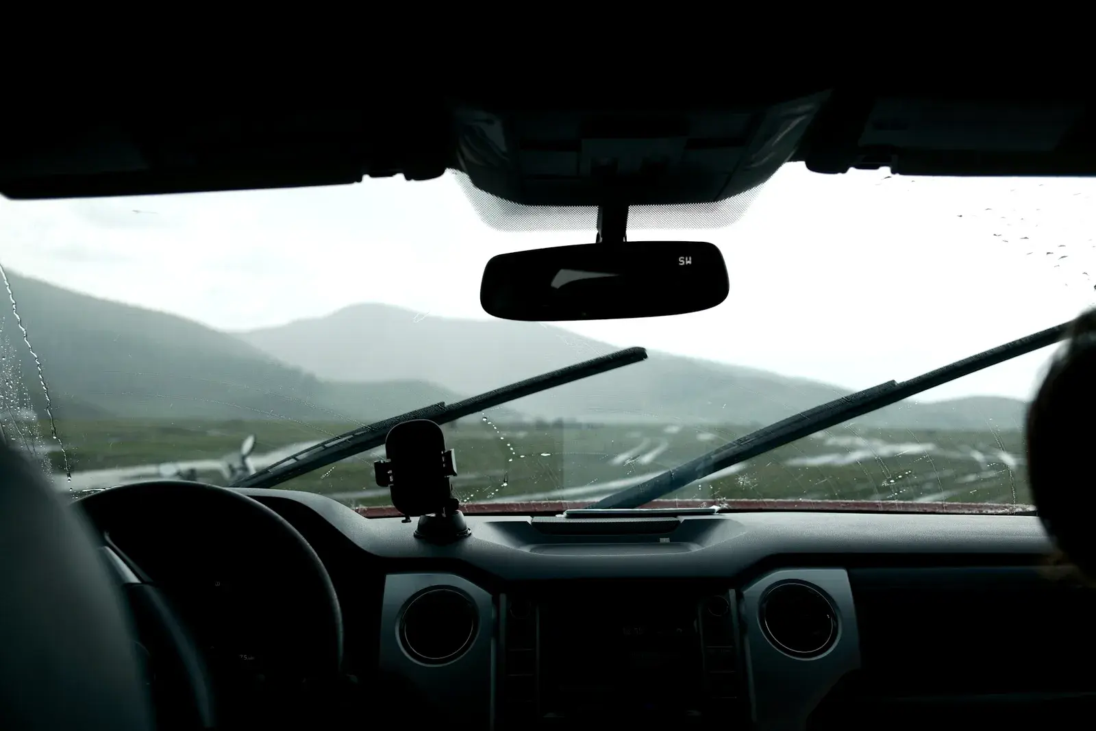 Vista de dentro do carro pelo para-brisa molhado de chuva. Imagem ilustrativa.